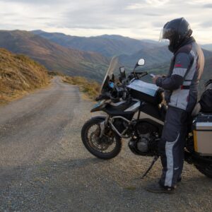 Motorista preparando un Viaje autoguiado en moto por una carretera de montaña