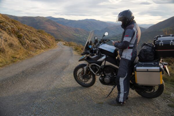 Motorista preparando un Viaje autoguiado en moto por una carretera de montaña